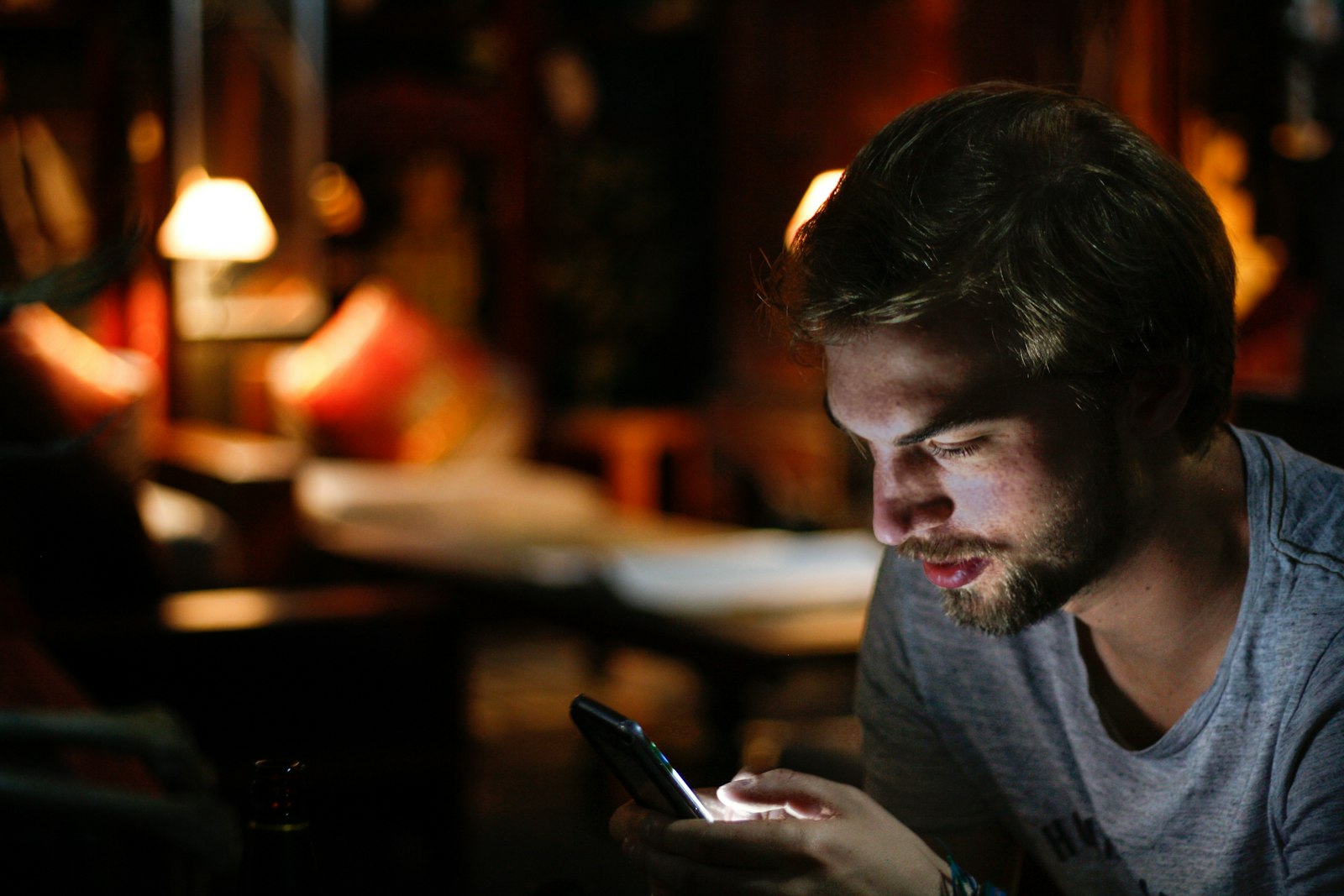 A man reading a text message in a warmly lit room